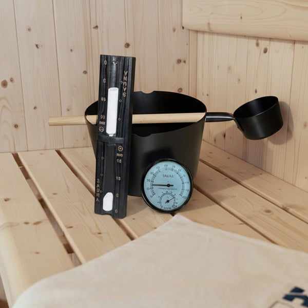 Sauna Zubehör Set bestehend aus Eimer mit Schöpfkelle, Sanduhr und Thermometer auf einer Saunabank aus Holz.