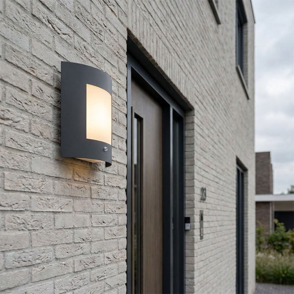 Moderne Außenwandleuchte in Anthrazit an einer hellen Klinkerfassade neben einem Hauseingang.