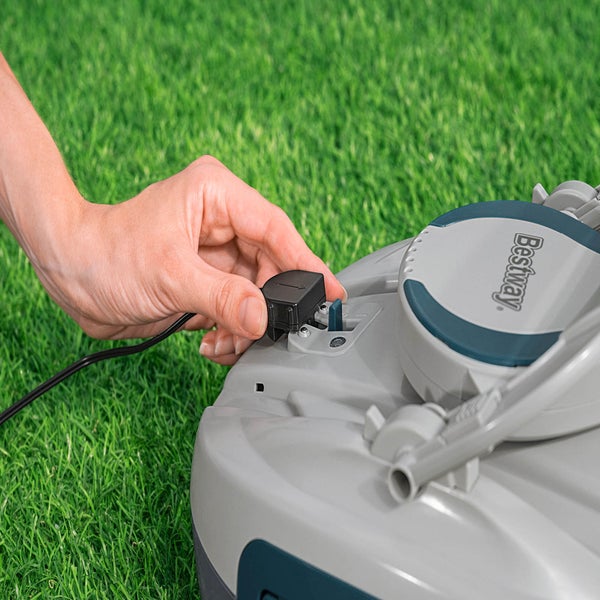 Eine Hand schließt das Stromkabel an einen Rasenmäherroboter der Marke Bestway an.