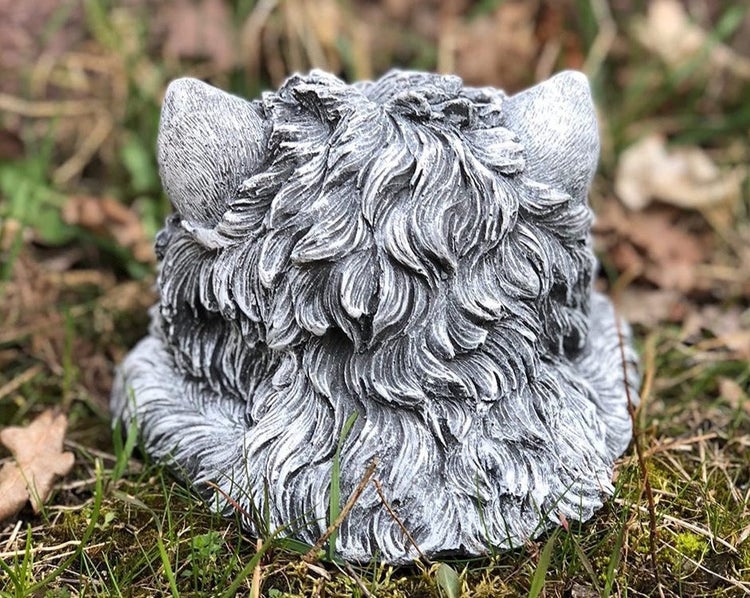 Detaillierte Rückansicht einer steinernen Tierfigur als Gartendekoration im Gras.