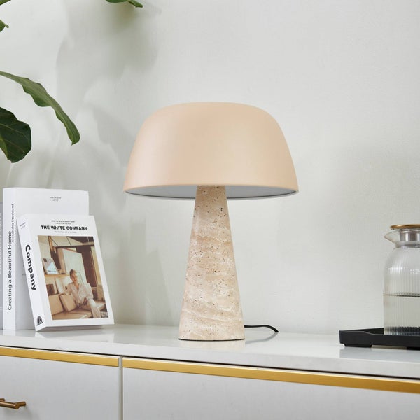 Moderne Tischleuchte mit kegelförmigem Sockel aus Naturstein und beigem Kuppelschirm auf einem weißen Sideboard.