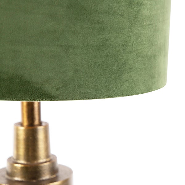Nahaufnahme einer Tischleuchte mit einem Lampenschirm aus grünem Samt und einem messingfarbenen Metallsockel.