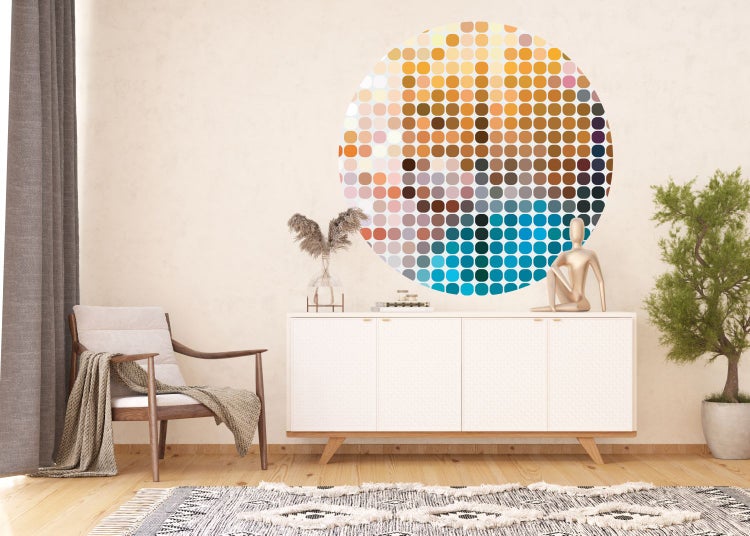 Wohnzimmer mit Sessel, Kommode und rundem Wandbild aus bunten Kreisen