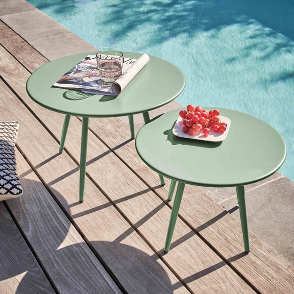 Zwei Gartenstühle aus Holz mit Geflecht und ein runder grüner Beistelltisch auf einer Rasenfläche am Pool.