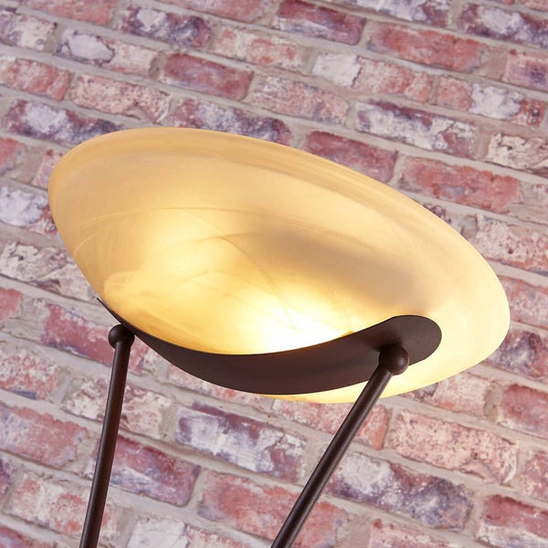 Stehleuchte mit Glasschirm und Metallgestell vor einer Backsteinwand