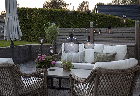 Szene einer Terrasse mit Gartenmöbeln und Beleuchtung