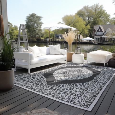Terrasse mit gemustertem Teppich, Sofa, Hocker und Blick auf den See