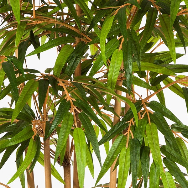 Detailaufnahme einer künstlichen Bambuspflanze mit grünen Blättern und braunen Stielen.