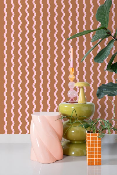 Szene mit gemusterter Tapete, Beistelltisch, Kerzenständer und Zimmerpflanzen.