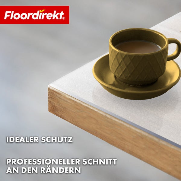 Detailansicht einer Tischkante mit Kantenschutz und einer Tasse auf einem Untersetzer. Floor direkt Logo.