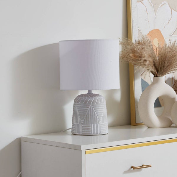 Dekorative Tischleuchte mit geometrischem Muster und Stoffschirm auf einer Kommode