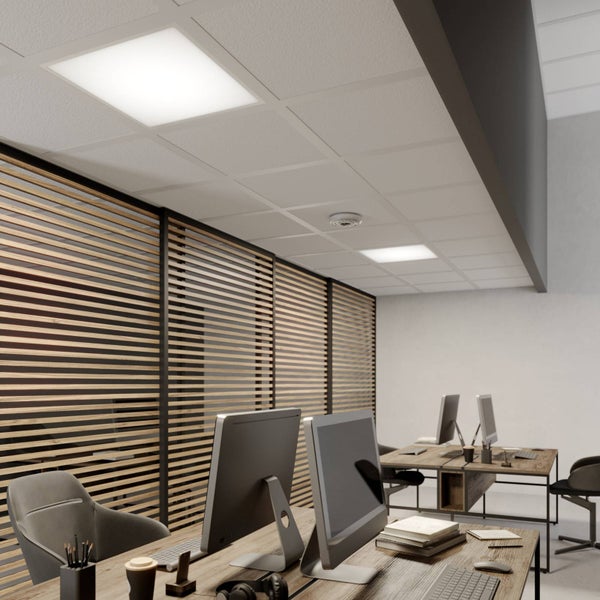 Quadratisches LED Panel in einer Rasterdecke über einem modernen Büroarbeitsplatz mit Holztischen und einer Trennwand aus Holzlamellen.