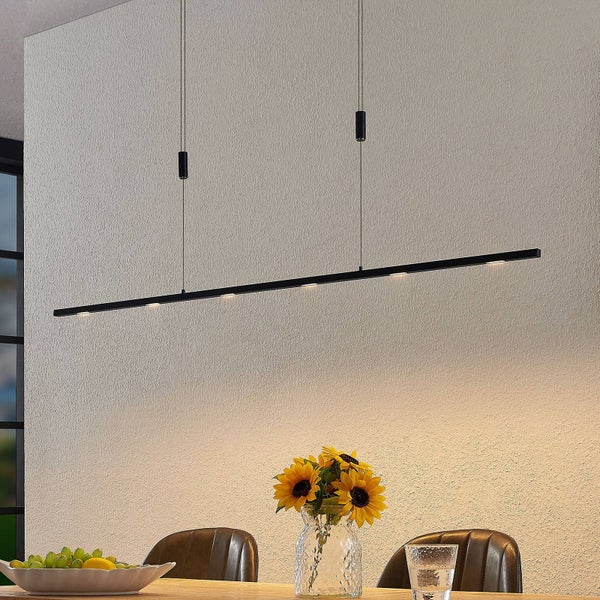 Lineare LED-Pendelleuchte in Schwarz über einem Esstisch mit Sonnenblumen und Stühlen in einem hellen Essbereich.