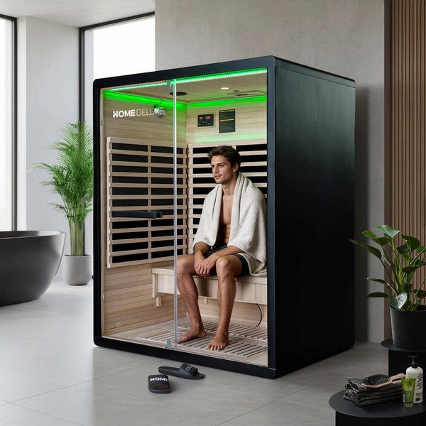 Ein Mann sitzt in einer modernen Infrarotkabine von Home Deluxe in einem hellen Wellness Badezimmer.
