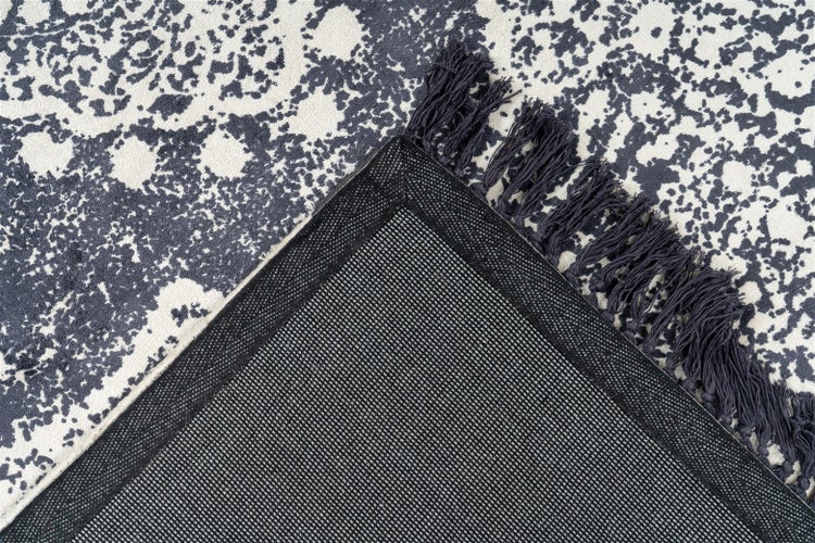 Teppich mit abstraktem Muster, dunklen Fransen und strukturierter, rutschfester Rückseite.