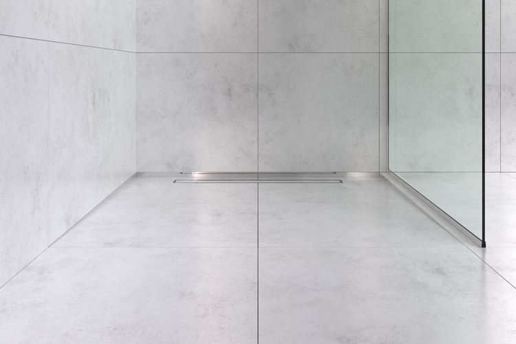 Bodengleiche Dusche mit großformatigen Fliesen in Betonoptik, einer Duschrinne aus Edelstahl und einer gläsernen Trennwand.