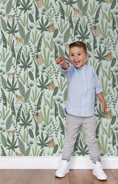 Kind vor einer Dschungeltapete mit Affenmotiven