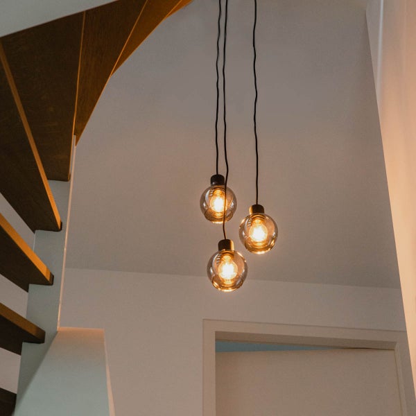 Moderne Hängelampe mit drei Glaskugeln neben einer Holztreppe