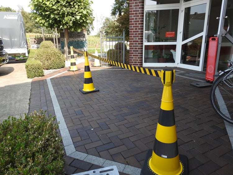 Ein Zimmer mit einer verzierten floralen Tapete, einem schwarzen Tisch mit Bank, einem Regal und einem Teppich mit Kreismuster.