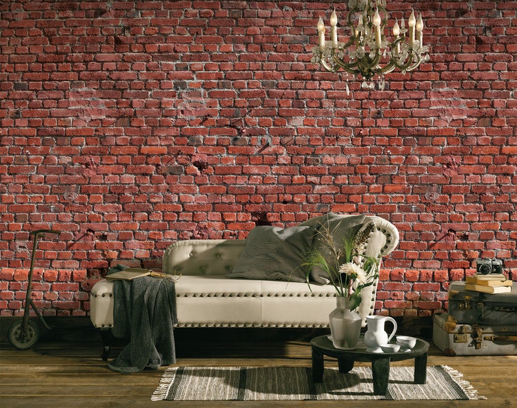 Vliestapete mit roter Backsteinoptik in einem rustikalen Wohnzimmer mit beiger Recamiere, Holzboden und Kronleuchter.