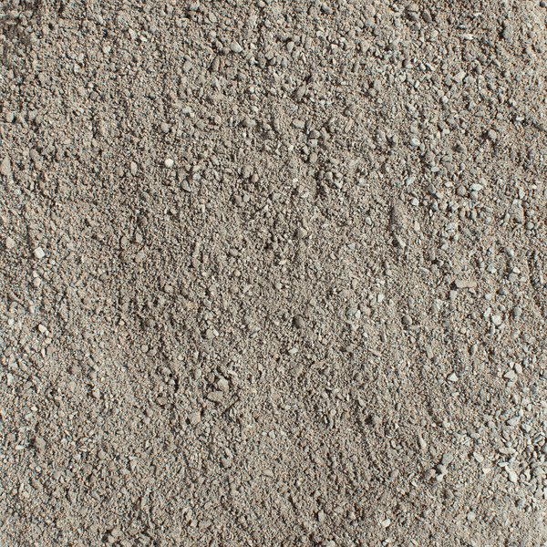 Ein Mann verteilt Pflastersplitt mit einem Rechen auf einer gepflasterten Fläche.