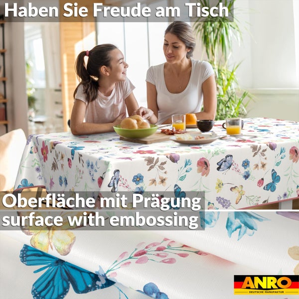 Helle Szene mit Frau und Kind an einem Tisch mit einer geprägten Wachstuchtischdecke mit Blumen- und Schmetterlingsmuster. ANRO Logo.