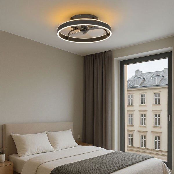 Moderner Deckenventilator mit LED-Lichtring in einem hellen Schlafzimmer mit Doppelbett, Fensteraussicht und ruhiger Atmosphäre.