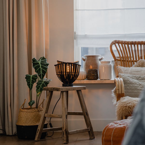 Dekorative Szene mit Tischleuchte aus Rattan, Pflanzenkorb und Rattansessel für Wohnraumgestaltung