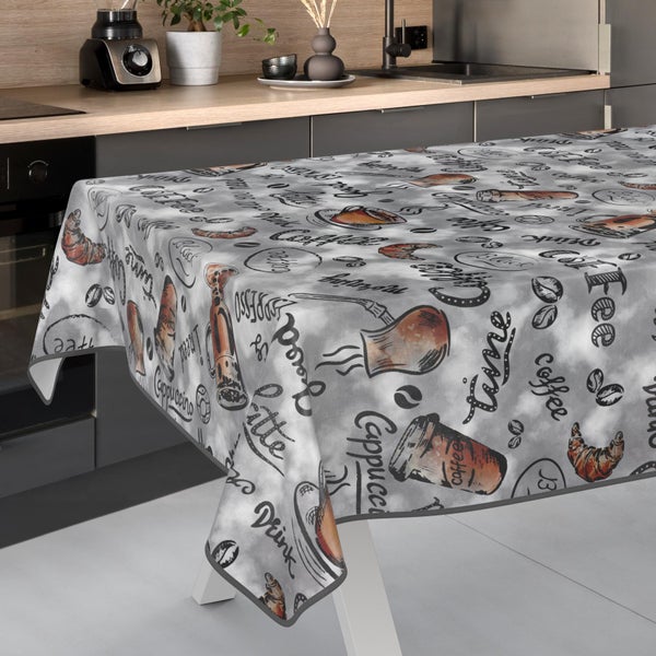 Tischdecke mit Kaffeemotiven wie Tassen, Bohnen und Schriftzügen in einer modernen Küche mit Holzarbeitsplatte.