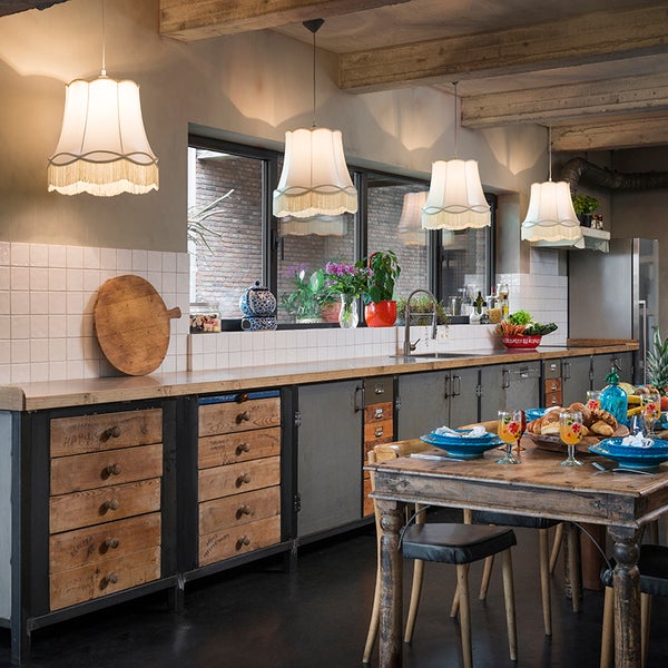 Rustikale Küche im Industriedesign mit Holzschubladen, Metallschränken, Stoffpendelleuchten und einem gedeckten Esstisch aus Holz.