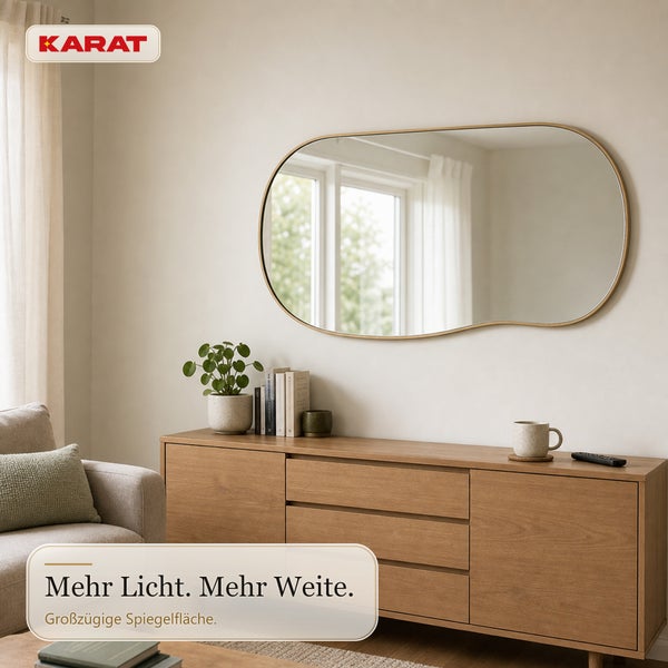 Karat Logo, ovaler Wandspiegel mit schmalem Rahmen über einem hölzernen Sideboard in einem hellen, wohnlich eingerichteten Zimmer.