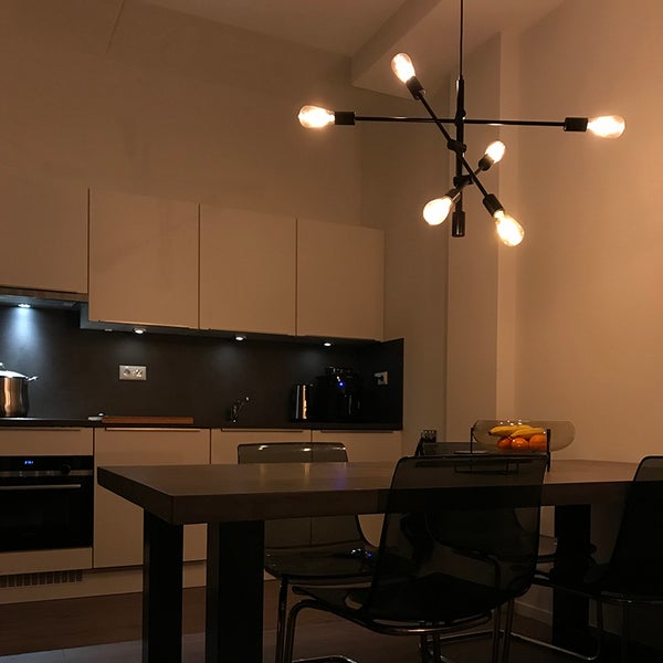 Moderne Küche mit einer Hängeleuchte im Sputnik Design über einem Esstisch mit transparenten Stühlen und einer dunklen Arbeitsplatte.