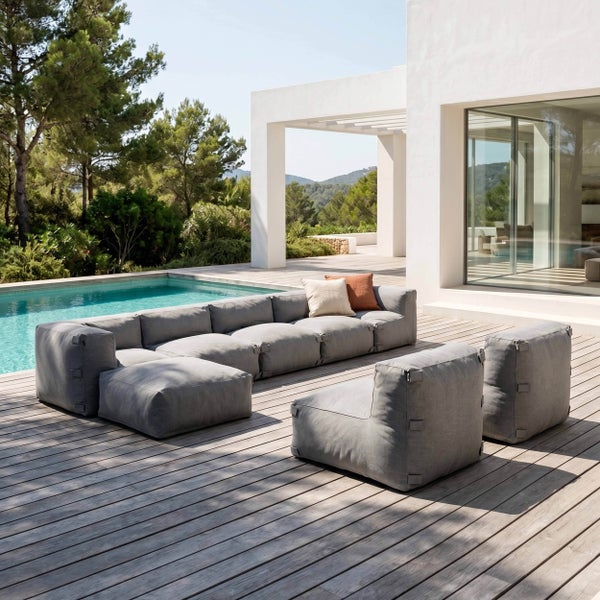 Modernes graues modulares Outdoor-Lounge-Set auf einer Holzterrasse am Pool, bestehend aus einem Ecksofa, Sesseln und Kissen.