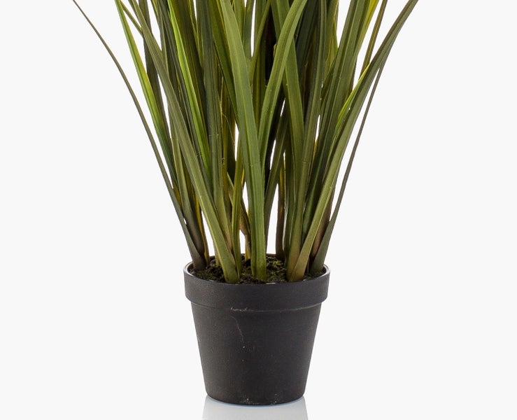 Nahaufnahme einer Kunstpflanze mit langen schmalen grünen Blättern.