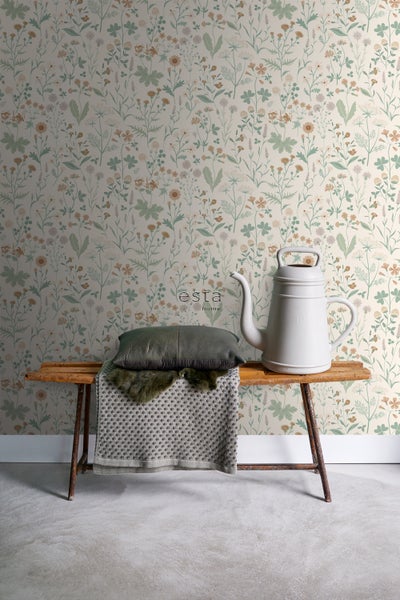 Dekorative Tapete mit Pflanzenmotiven hinter einer Bank mit Kissen und Gießkanne
