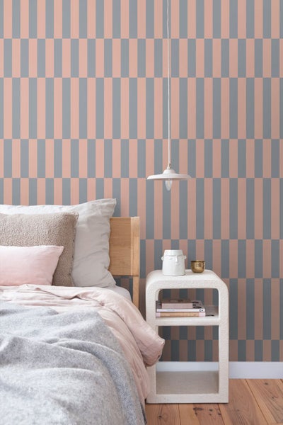 Modernes Schlafzimmer mit geometrischer Vliestapete, Bett aus Holz, Beistelltisch und Pendelleuchte in heller, organisierter Atmosphäre.