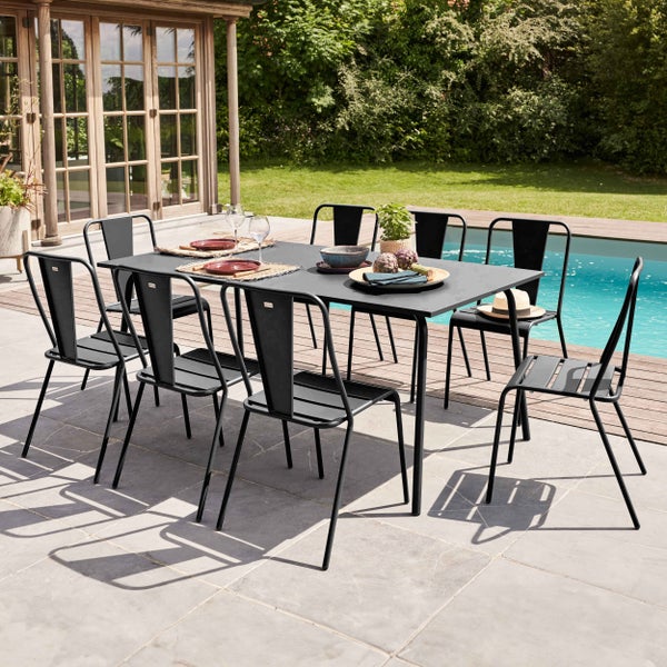 Gartentisch-Set mit rechteckigem Tisch und acht schwarzen Metallstühlen auf einer Terrasse neben einem Pool im Garten.