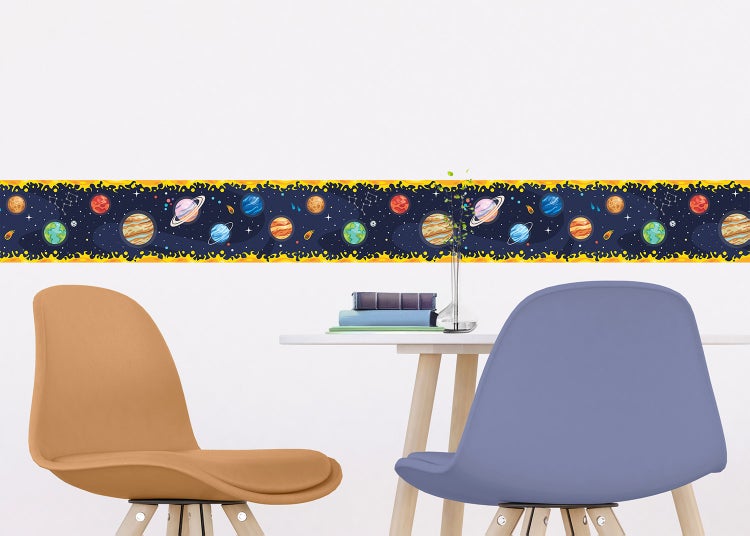 Selbstklebende Wandbordüre mit Weltraum-Motiv und Planeten in einem hellen Kinderzimmer über einem Schreibtisch mit Spielzeug.
