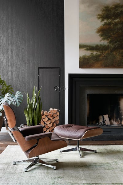 Wohnzimmer mit braunem Ledersessel und Fußhocker, Kamin und Holzstapel