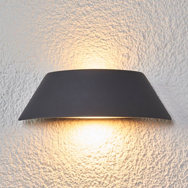 Moderne Außenwandleuchte in Anthrazit mit Lichtaustritt nach oben und unten an einer strukturierten Wand.
