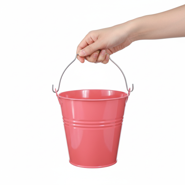 Hand hält einen kleinen rosa Metalleimer mit Henkel.
