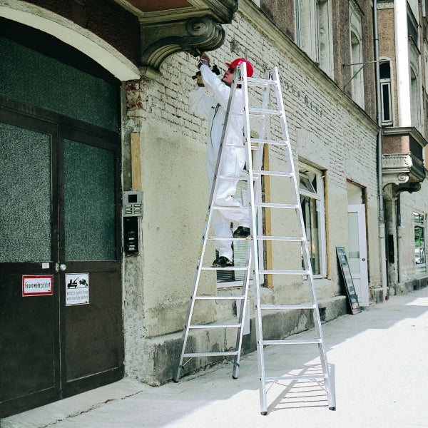 Handwerker auf einer Aluminiumleiter bei der Reparatur eines Gebäudes.
