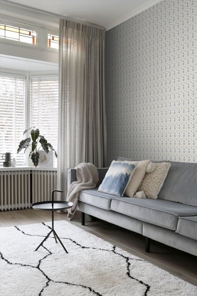 Wohnzimmer mit Sofa, gemusterter Tapete, Vorhängen, Teppich und Beistelltisch