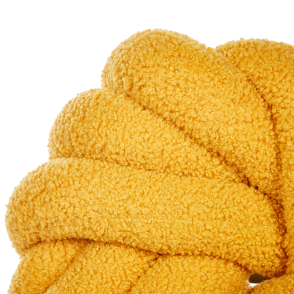Nahaufnahme eines gelben Knotenkissens mit Bouclé-Oberfläche.