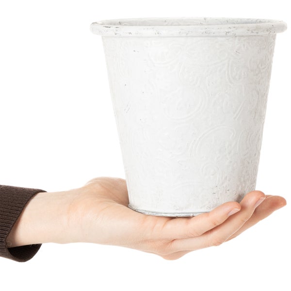 Weißer Übertopf mit Reliefmuster, in einer Hand gehalten.