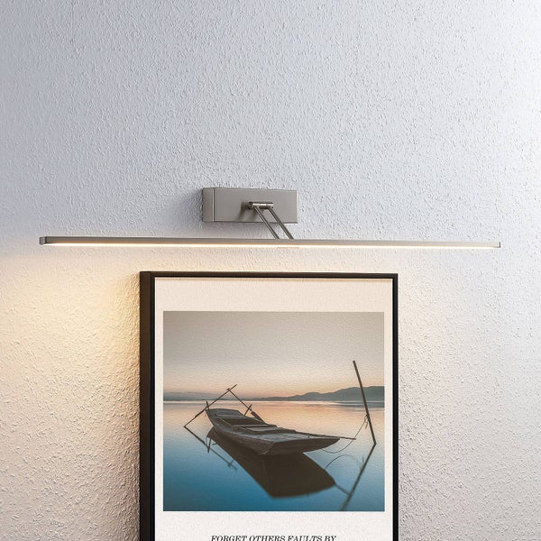 Moderne LED-Bilderleuchte aus Metall, montiert über einem gerahmten Bild an einer Wand.