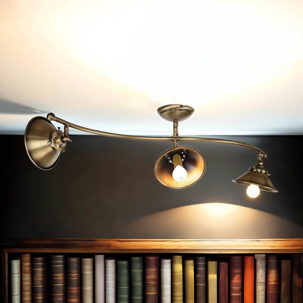 Deckenleuchte mit drei Strahlern aus Metall über einem Bücherregal