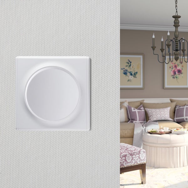 Ein weißer Drehdimmer an einer strukturierten Wand, im Hintergrund ein Ausschnitt eines Wohnzimmers mit Sofa, Hocker und Kronleuchter.