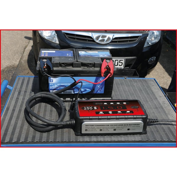 Batterieladegerät für 12 Volt und 24 Volt Blei-Säure-Batterien mit Autobatterie im Hintergrund