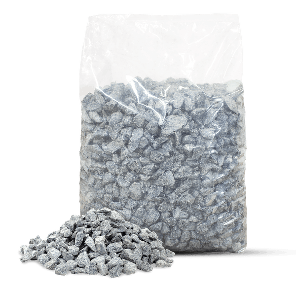 Grauer Edelsplitt in einem transparenten Beutel und ein kleiner Haufen Steine davor.